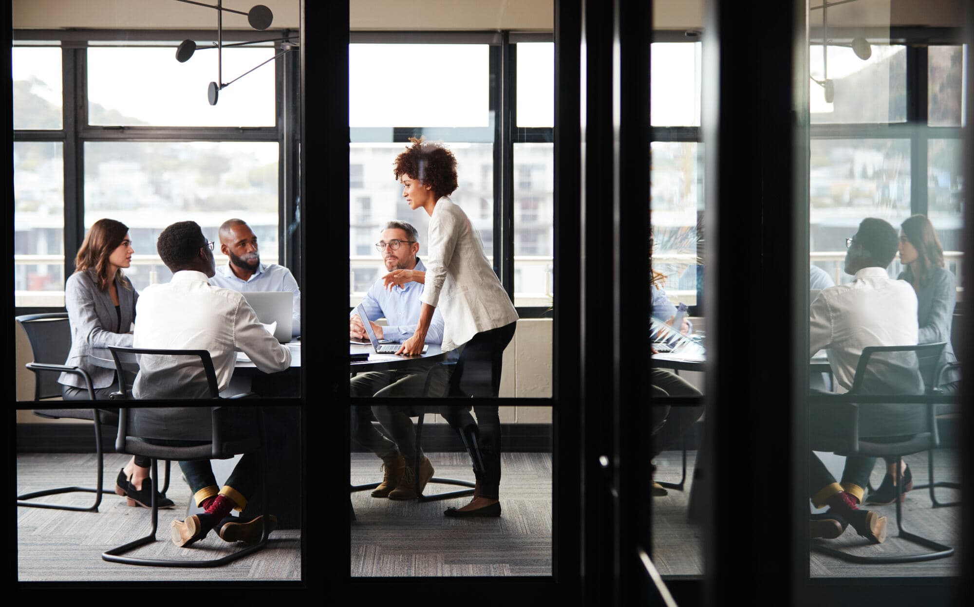 Teams collaborating in a glass-walled meeting room